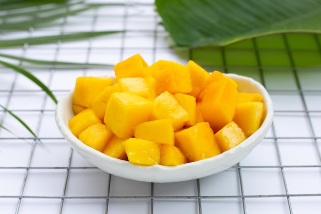 Frutas tropicales, rodajas de cubo de mango en tazón de fuente blanco