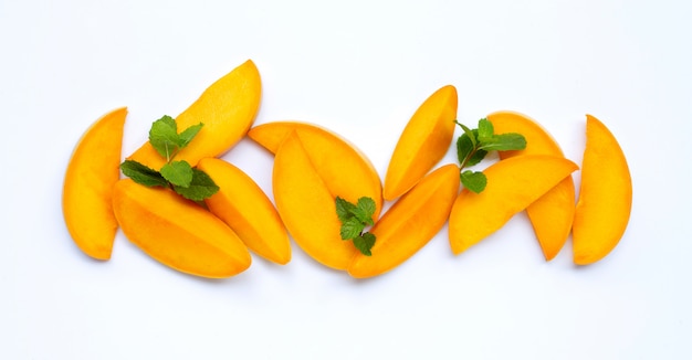 Frutas tropicales, rodajas de mango con hojas de menta en blanco.