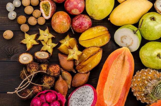 Frutas tropicales tailandesas clasificadas en un fondo rústico de madera oscuro.