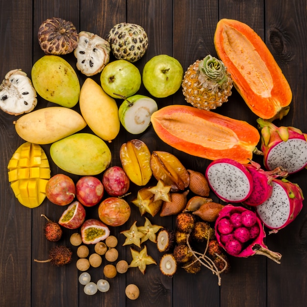 Frutas tropicales tailandesas clasificadas en un fondo rústico de madera oscuro.