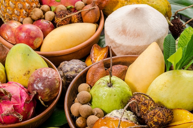 Frutas tropicales tailandesas clasificadas en un fondo rústico de madera oscuro.