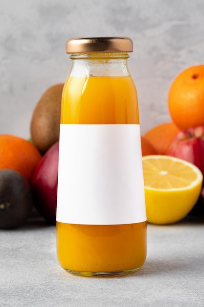 Frutas variadas e suco de frutas recém-espreitado em garrafa sobre fundo cinzento