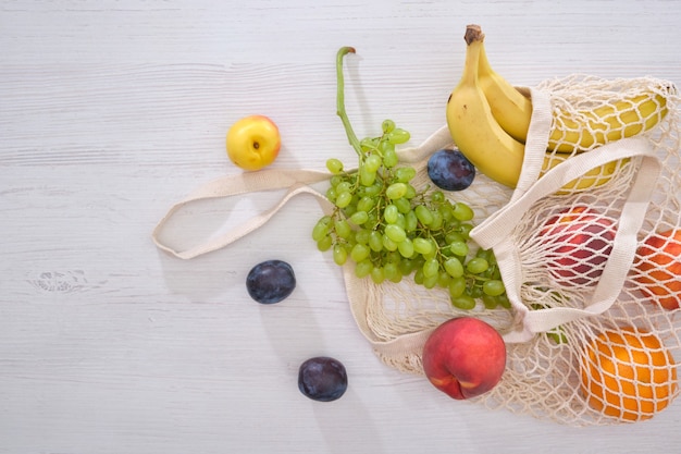 Frutas y verduras en una bolsa de malla sobre un fondo de madera