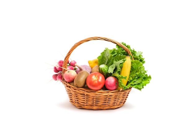 Frutas y verduras en una cesta de mimbre fondo blanco.