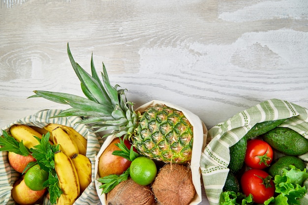 Frutas y verduras frescas en bolsas de algodón ecológico en la mesa en la cocina.