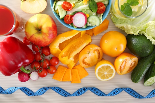 Frutas y verduras frescas con cinta métrica en la mesa de madera, vista superior