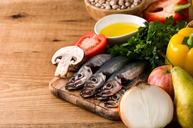 Frutas, verduras, granos, nueces, aceite de oliva y pescado en la mesa de madera.