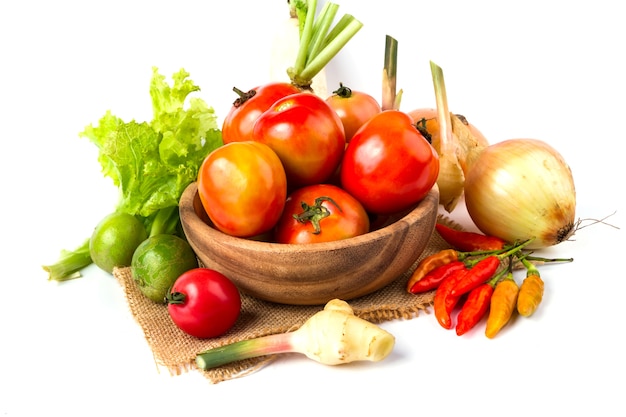 frutas y verduras en un tazón de madera sobre fondo blanco, tomate, limón, guindilla