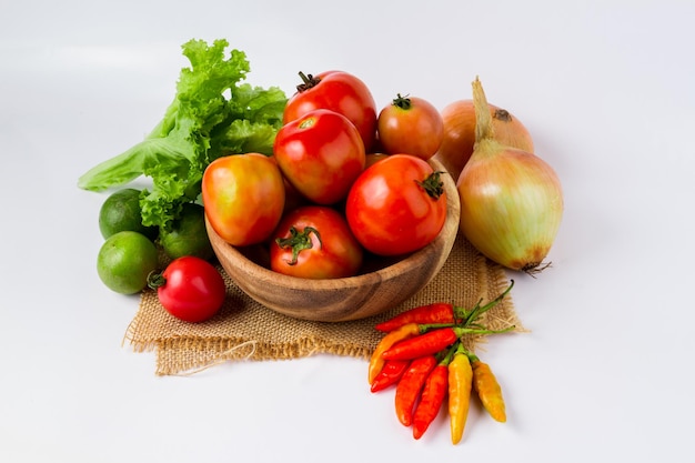 Frutas y verduras en un tazón de madera sobre fondo blanco