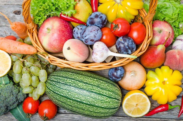 Frutas y verduras en la vista superior de la canasta. Sobre una mesa de madera.