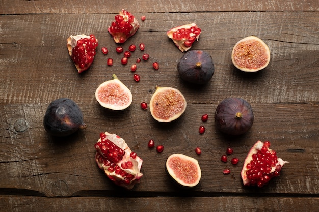 Frutifica a romã e os figos contra a tabela de madeira velha.