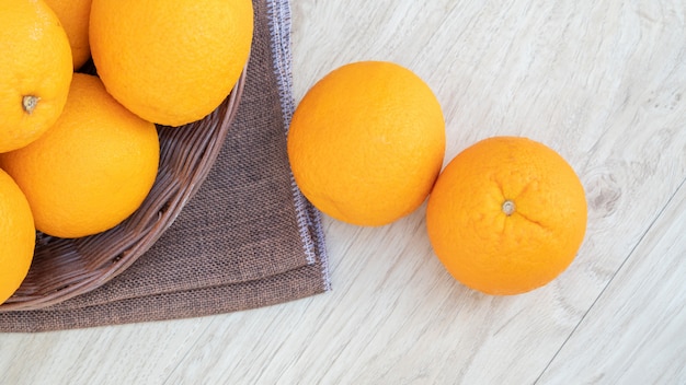 Fruto das laranjas em uma cesta em uma tabela de madeira.