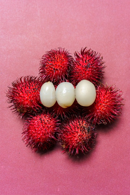 Fruto de rambutan de carne fresca em fundo vermelho O rambutan é uma fruta tropical