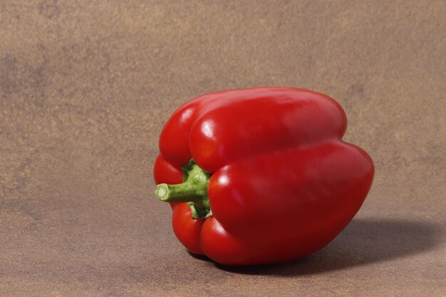 El fruto del pimiento dulce rojo sobre un fondo de mesa marrón