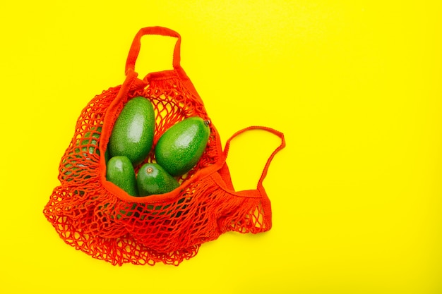 Foto frutos de aguacates en bolsa ecológica de malla roja reutilizable