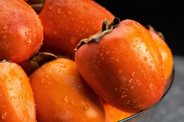 Frutos de caqui con gotas de agua sobre fondo negro