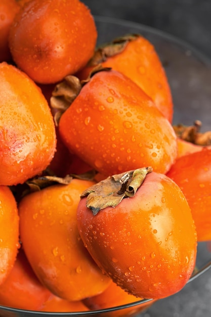 Frutos de caqui con gotas de agua sobre fondo negro