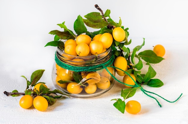 Frutos de ciruela cereza en un vaso jaron un fondo blanco Enfoque suave