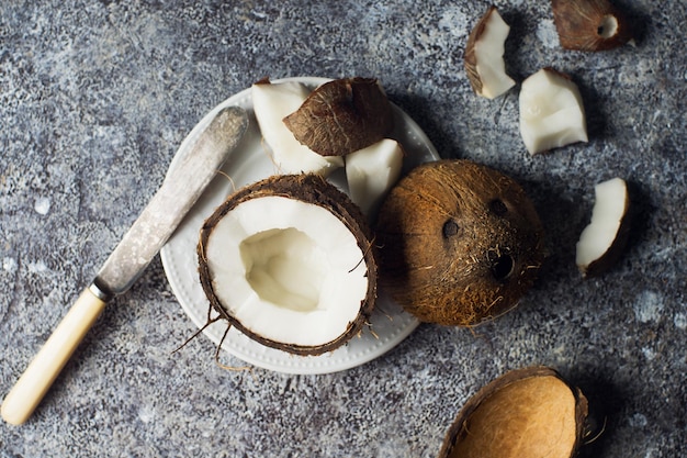 Frutos de coco maduros frescos en mitades sobre fondo de piedra oscura