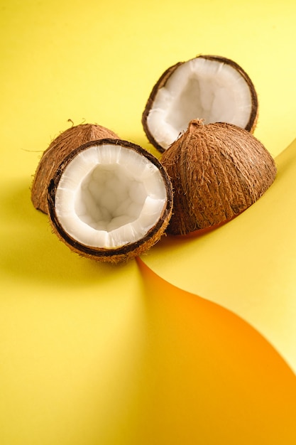 Frutos de coco en papel doblado amarillo pared simple, comida abstracta concepto tropical, ángulo de visión