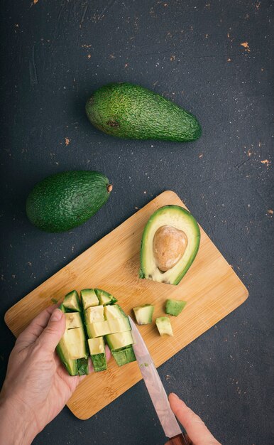 Foto frutos de abacate maduros e saborosos em uma tábua de cortar com uma faca