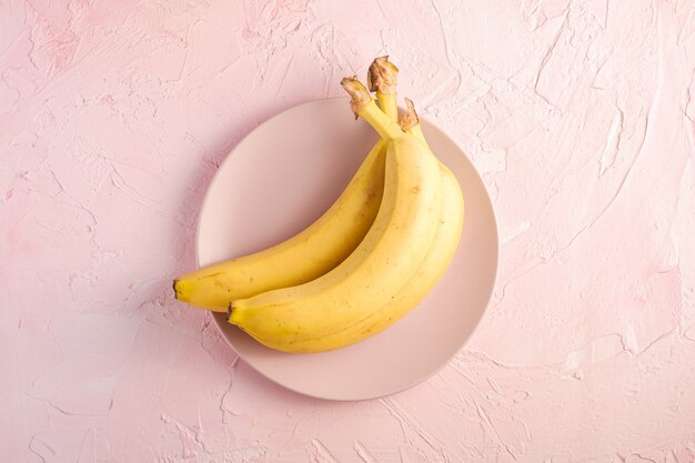 Frutos de banana em chapa rosa na superfície texturizada rosa