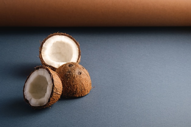 Frutos de coco na superfície do papel dobrado cinza marrom e azul, conceito tropical de comida abstrata, espaço de cópia de vista de ângulo