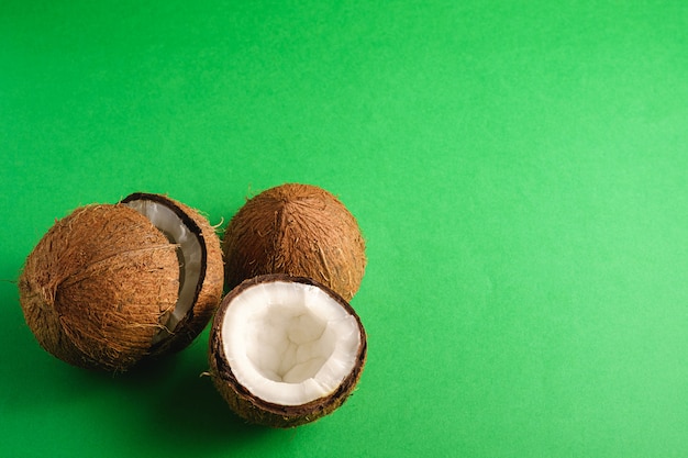 Frutos de coco no fundo liso verde, conceito tropical de comida abstrata, espaço de cópia de vista de ângulo