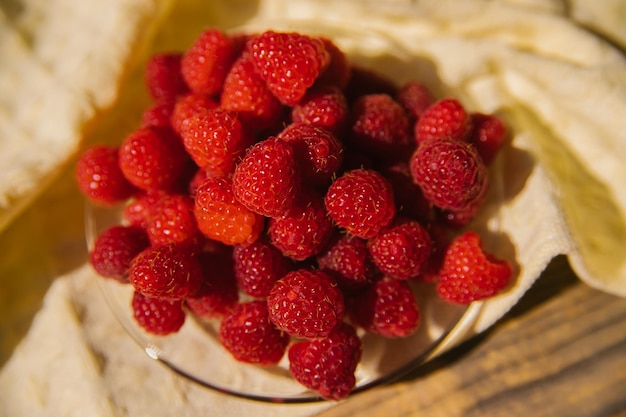 Frutos de framboesa em um pequeno pires um monte de bagas de verão em um fundo de madeira Fundo de verão Aperitivo suculento ou sobremesa