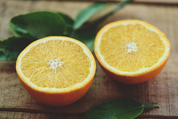 Frutos de laranja com folha em fundo de madeira, fatia de laranja fresca e frutos saudáveis de folhas