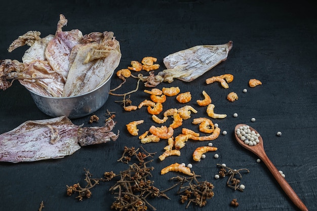 Frutos do mar secos com lulas secas e camarão seco em uma mesa de madeira preta