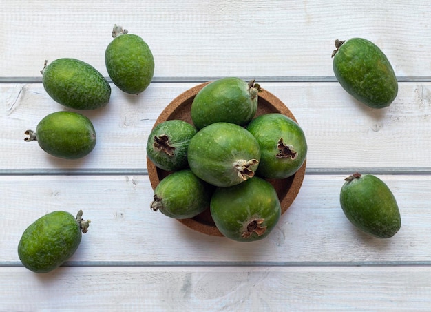 Frutos de feijoa verde en un plato de corcho sobre una mesa de madera blanca clara