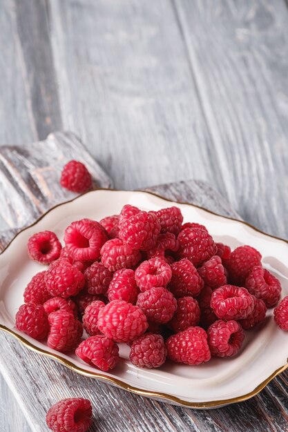 Frutos de frambuesa en placa sobre tabla de cortar antigua