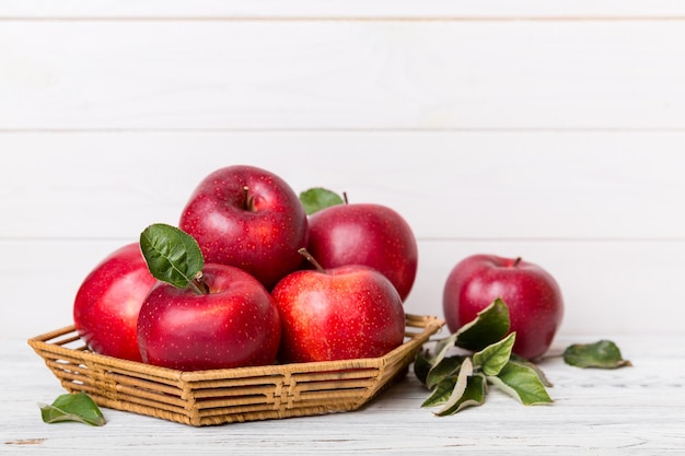 Frutos maduros de maçã jardim com folhas na cesta na mesa de madeira. Vista superior plana com espaço de cópia