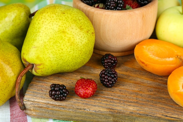 Frutos maduros e bagas na tigela na mesa de perto