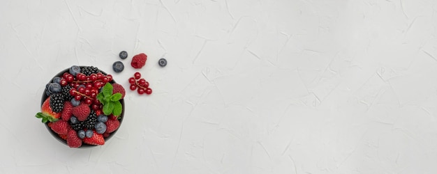 Foto frutos maduros e doces diferentes em uma tigela na mesa de madeira. conceito de colheita. amoras frescas.