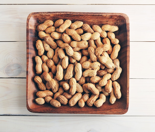 Frutos de maní con cáscara en placa de madera