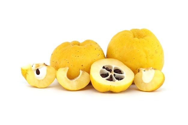 Los frutos del quince amarillo entero y algunos cortados por la mitad para exponer sus semillas aisladas sobre un fondo blanco