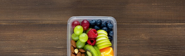 Frutos sanos con almendras en una caja para llevar sobre fondo de madera de banner