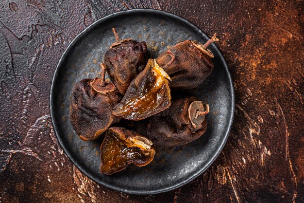 Frutos secos de caqui em um prato Fundo escuro Vista superior