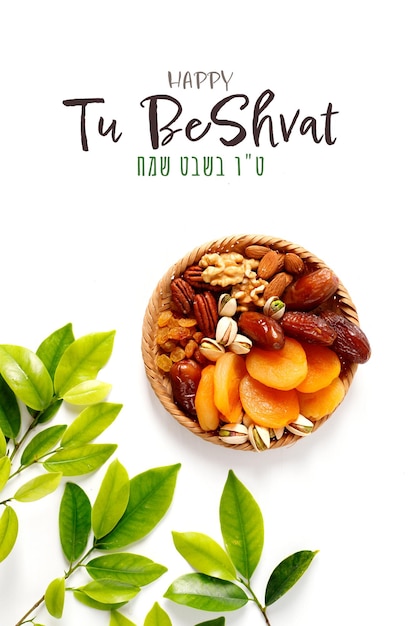 Frutos secos y nueces mezclados en una rama de placa de mimbre con hojas verdes jóvenes Concepto de la festividad judía Tu Bishvat sobre fondo blanco con espacio de copia