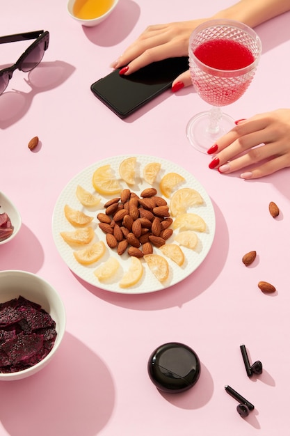 Frutos secos y nueces con salsa sobre fondo rosa con manos de mujer