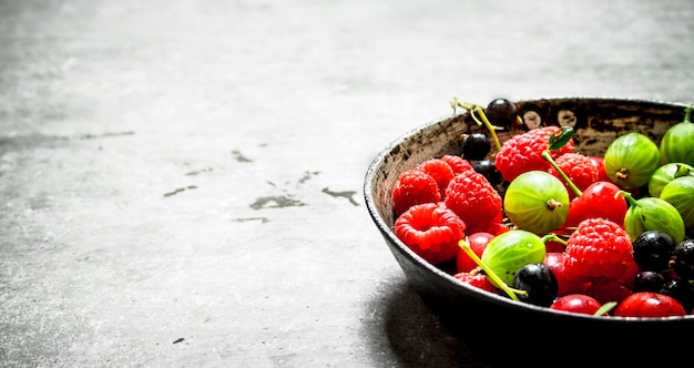 Frutos silvestres no velho prato na mesa de pedra.