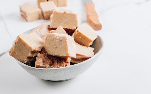 Fudge de mantequilla de maní vegano crudo sobre un fondo de mármol blanco Concepto de comida vegana saludable Enfoque selectivo