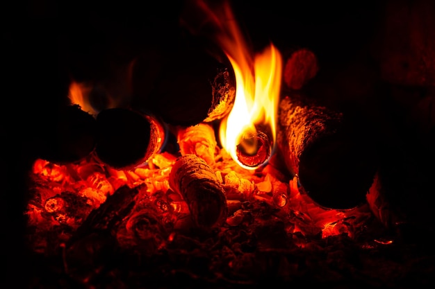 Fuego anaranjado en la chimenea, leños encendidos y carbones en la estufa.