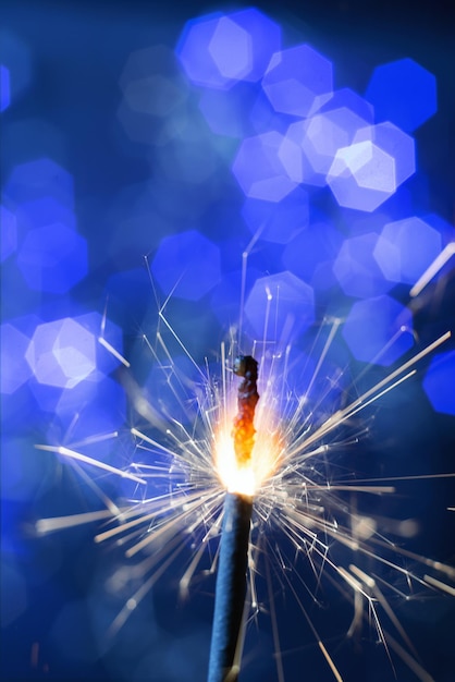 Foto fuego de año nuevo de bengala parpadeante ardiente en el fondo de luces azules bokeh