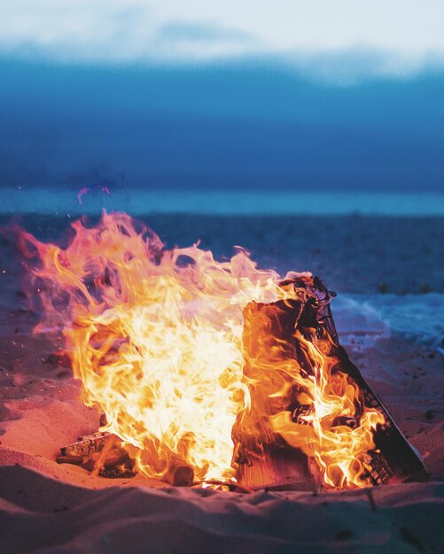 Fuego de campamento en la playa durante la puesta del sol