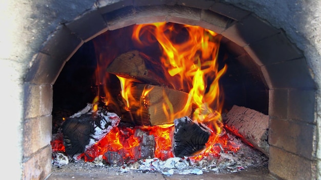 Fuego en la chimenea con troncos y llamas en casa de la quema de troncos de madera en llamas rojas