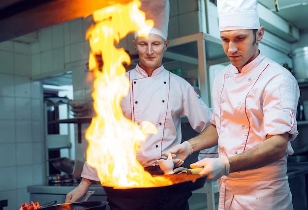 Fuego en la cocina. La quema de gas de fuego se está cocinando en una sartén de hierro, revuelva el fuego muy caliente