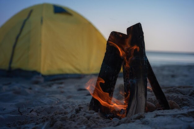 Fuego en hoguera en la playa Camping y carpas para viajar